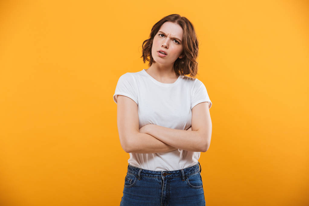 Image of displeased young lady standing isolated over yellow background looking camera. - Photo, Image