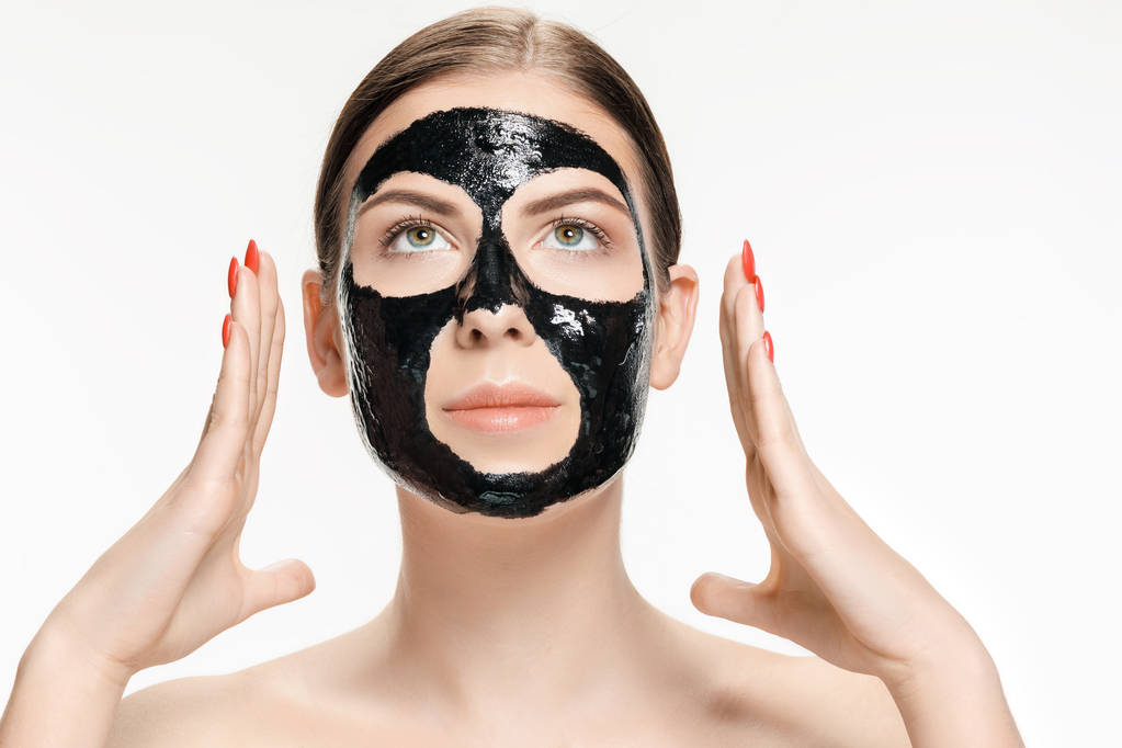 junge schöne Frau, die eine Maske für das Gesicht des therapeutischen schwarzen Schlammes aufträgt. Wellness-Behandlung - Foto, Bild