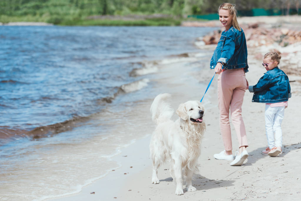 felice madre e figlia a piedi con cane golden retriever sulla riva del mare
 - Foto, immagini