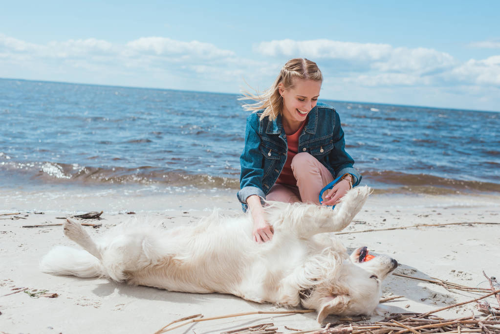 attraente donna felice giocando palla con cane golden retriever sulla riva del mare
 - Foto, immagini