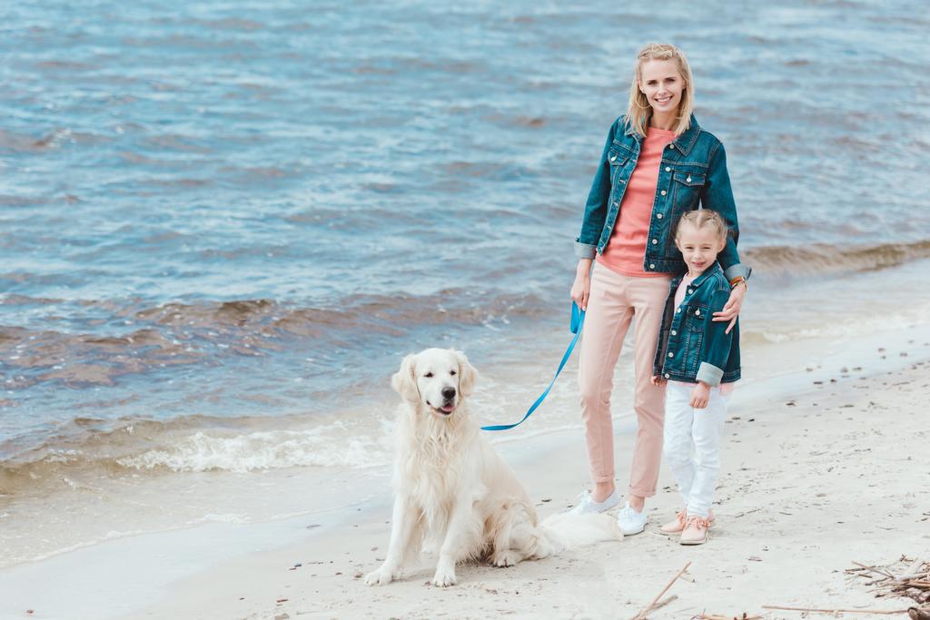 мать и дочь гуляют с собакой на берегу моря
 - Фото, изображение