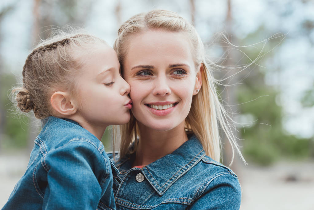 little adorable daughter kissing her blonde mother  - Photo, Image