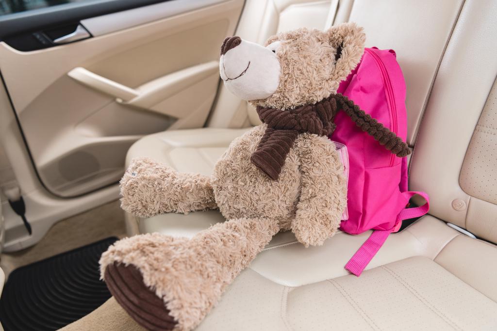車のシートにピンクのバックパックでテディベアのビューをクローズ アップ - 写真・画像
