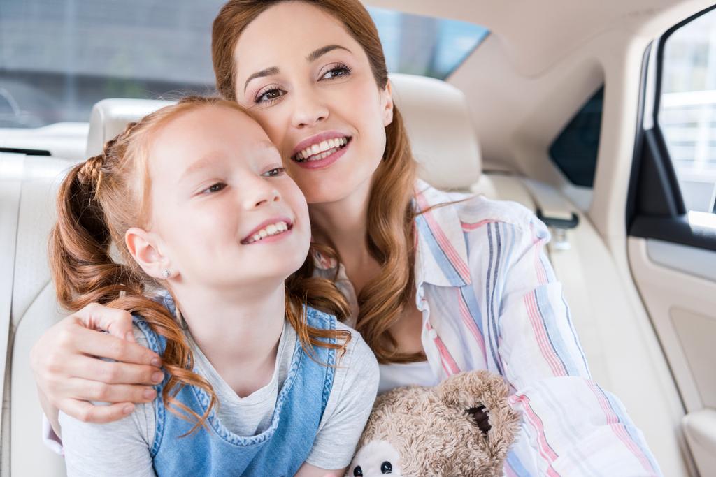 ritratto di madre e figlia felice con orsacchiotto seduto in macchina
 - Foto, immagini