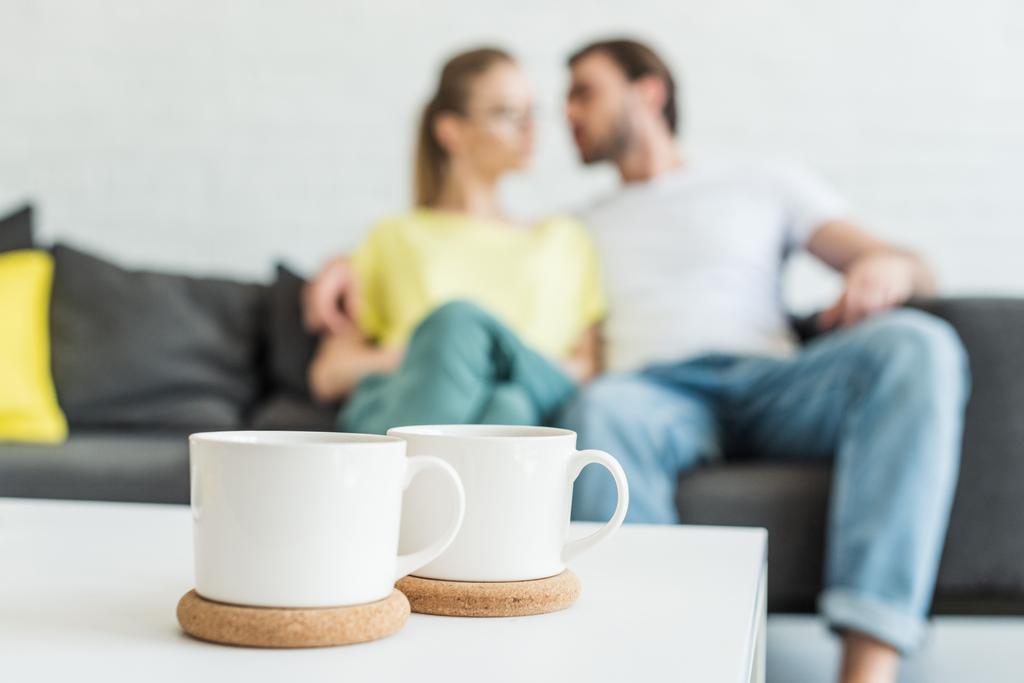 İki kahve fincanı ve koltuğun arkasına oturan çift yukarıya kapatmak  - Fotoğraf, Görsel