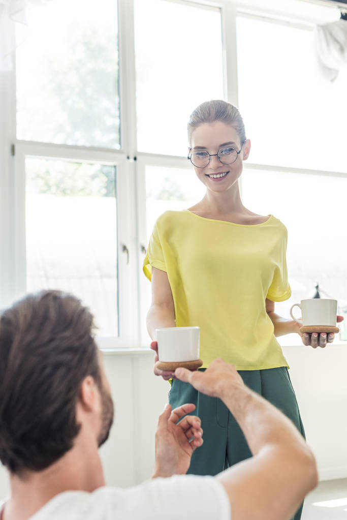 Gelukkig jonge vrouw in brillen koffiekopje geven vriendje  - Foto, afbeelding
