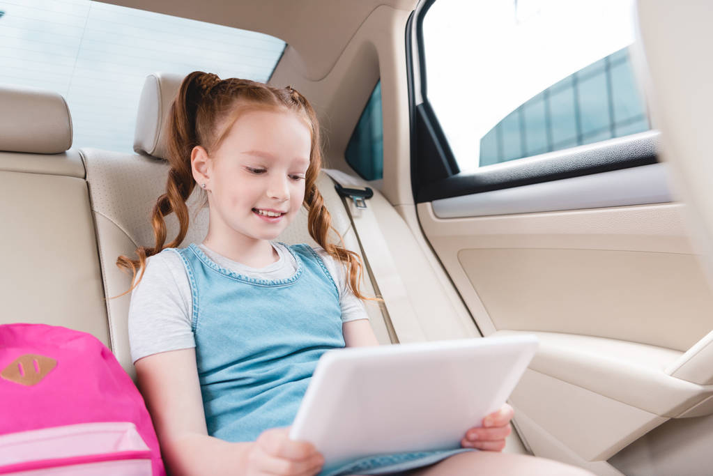 портрет усміхненої дитини, що використовує планшет, сидячи в машині
 - Фото, зображення