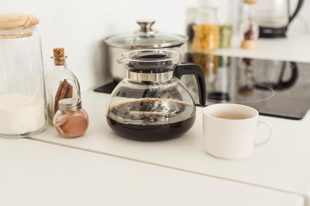 close up view of coffee maker, cup and glass jars near stove on tabletop at kitchen - Photo, Image