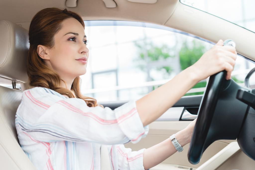 vista lateral de mujer atractiva conduciendo coche solo
 - Foto, Imagen