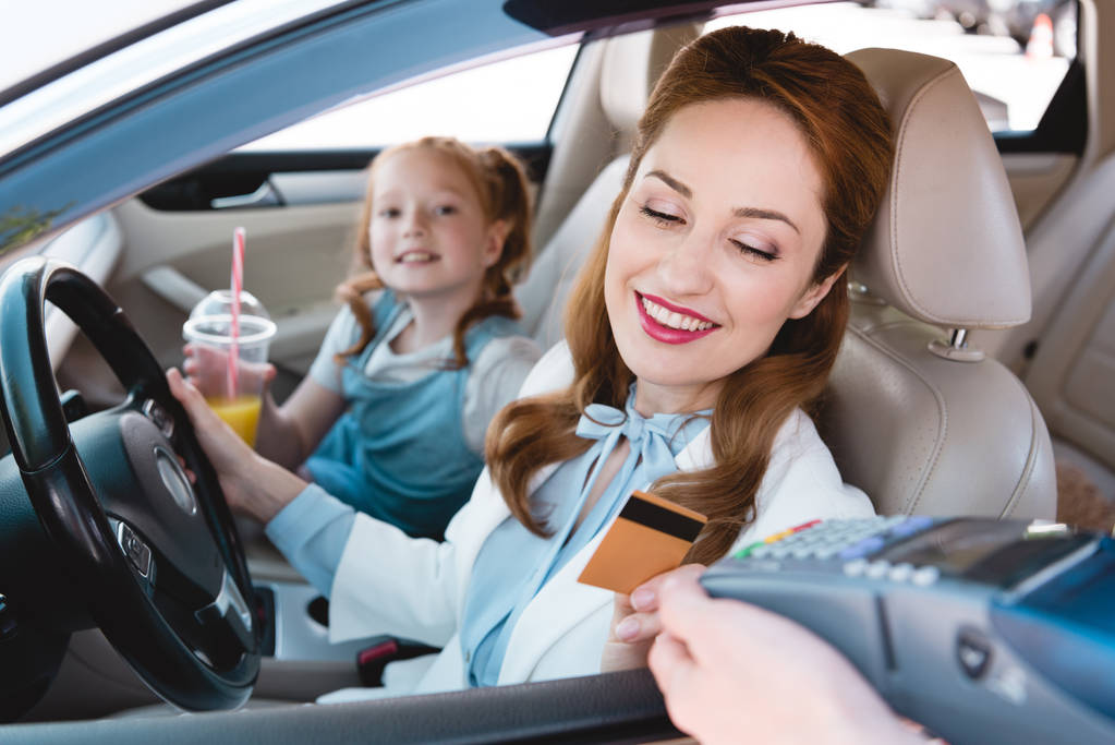 Glimlachende zakenvrouw betalen met credit card voor take away volgorde in auto - Foto, afbeelding