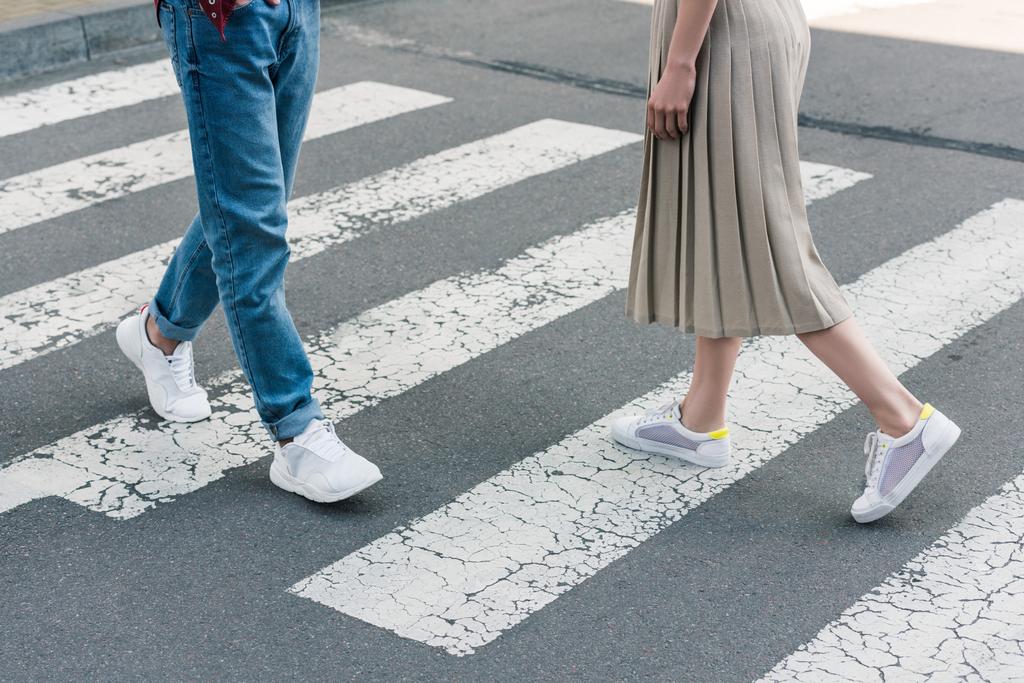 przycięte strzał stylowy Kobieta w spódnicy i człowieka w dżinsy, chodzenie na przejściu dla pieszych przy ulicy miasta - Zdjęcie, obraz