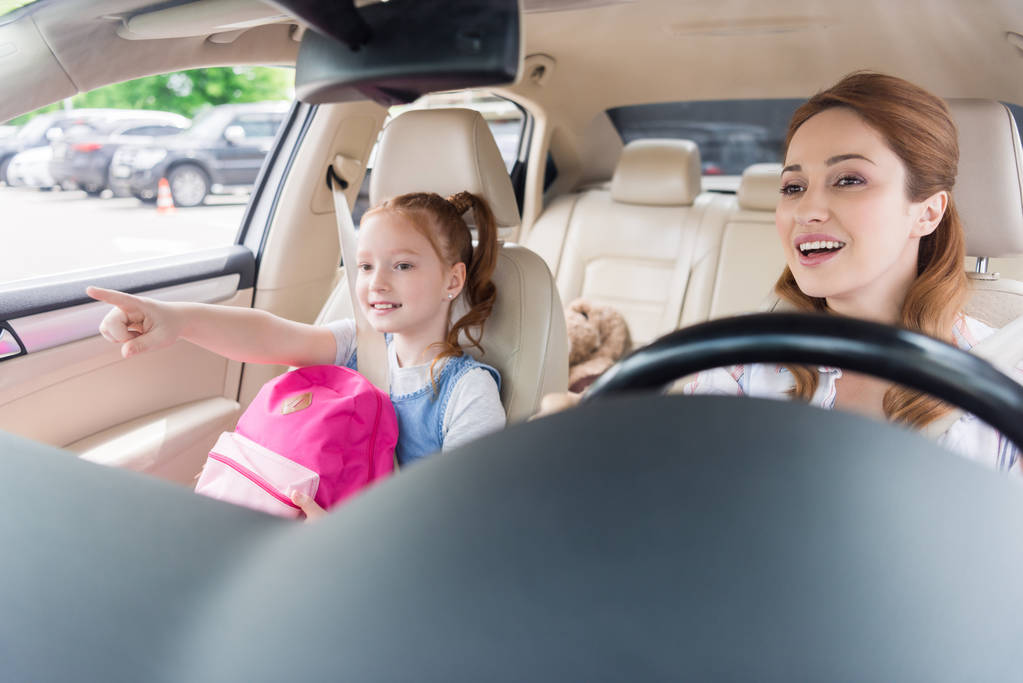 portrait d'une mère souriante conduisant une voiture avec sa fille pointant du doigt tout près
 - Photo, image