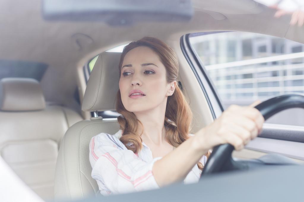 kuva naisesta, joka katsoo poispäin ajaessaan autoa
 - Valokuva, kuva