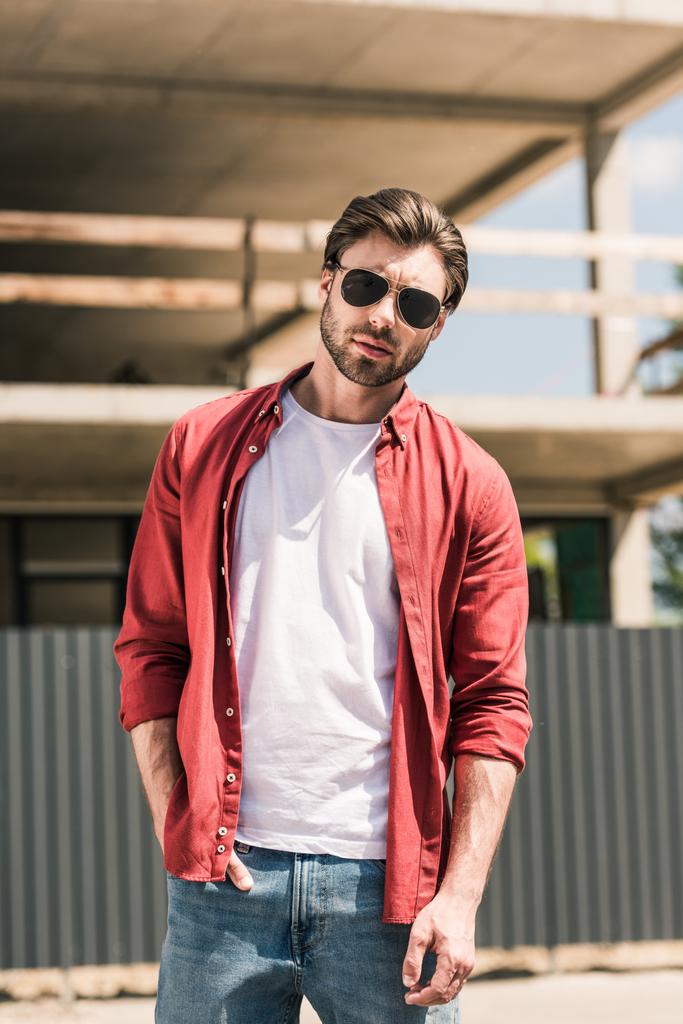 portrait of young stylish man in sunglasses posing in front of construction building  - Photo, Image