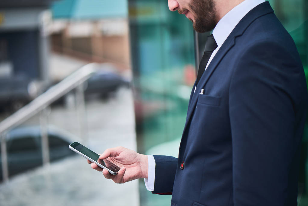 hombre de negocios barbudo en traje usando teléfono inteligente al aire libre, primer plano
  - Foto, Imagen
