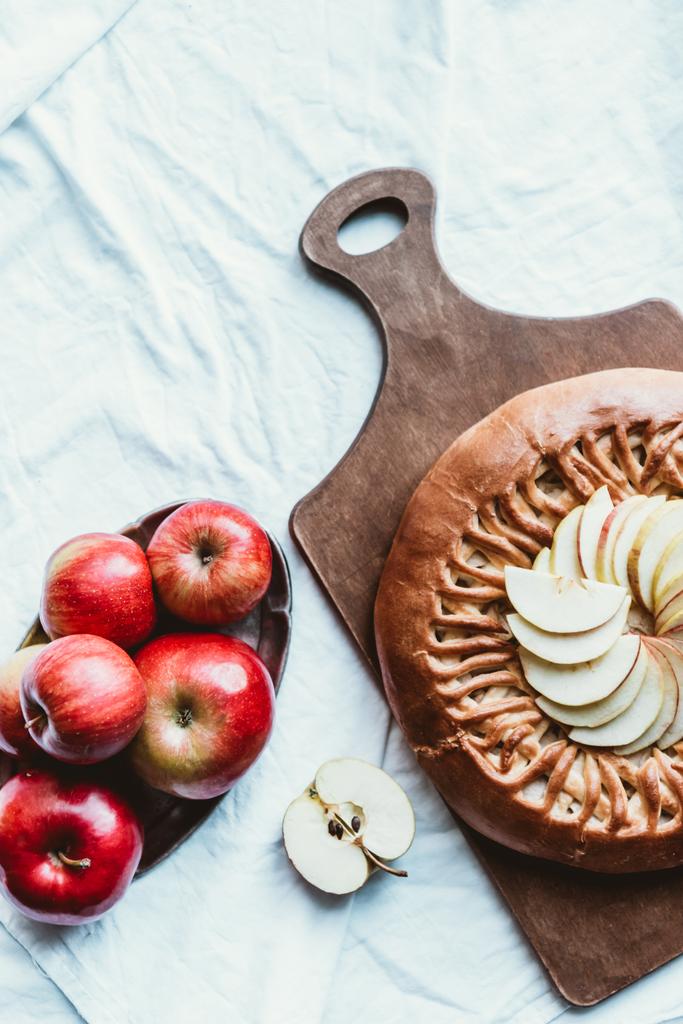 vista dall'alto di mele fresche e torta di mele fatta in casa su tagliere in legno su tovaglia bianca
 - Foto, immagini
