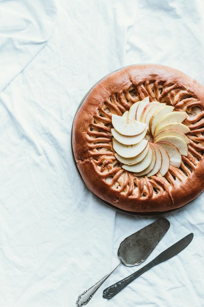 το Top view σπιτική μηλόπιτα, κέικ server και μαχαίρι σε λευκό τραπεζομάντιλο - Φωτογραφία, εικόνα