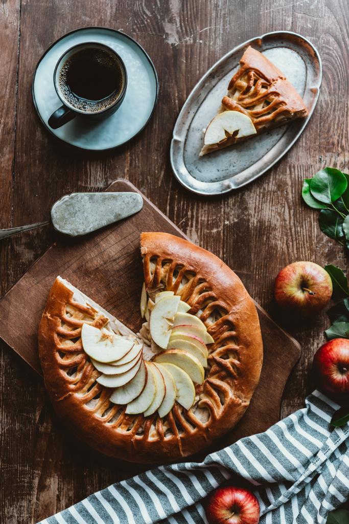 плоский лежав із шматочком домашнього яблучного пирога, сервером для торта, чашкою кави та свіжими яблуками на дерев'яній поверхні
 - Фото, зображення