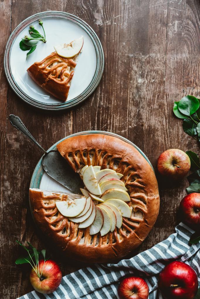 tendido plano con trozo de tarta de manzana casera, servidor de pastel y manzanas frescas en la superficie de madera
 - Foto, imagen
