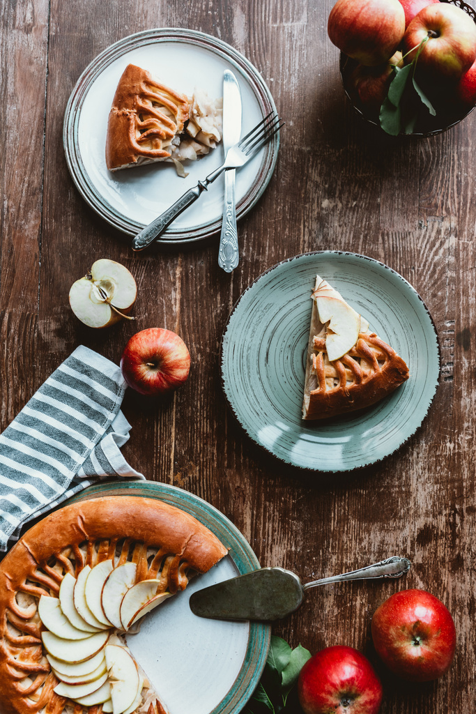 flat lay with pieces of apple pie on plates, cutlery and fresh apples on wooden tabletop - Photo, Image