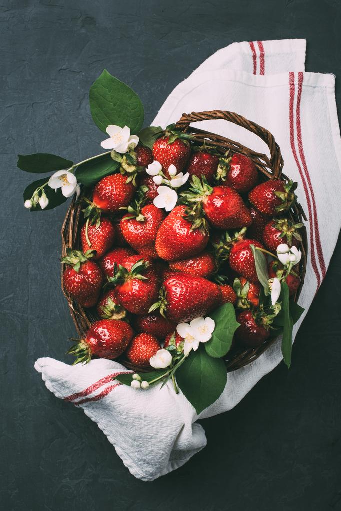 fresas frescas maduras y hermosas flores de jazmín en cesta sobre negro
 - Foto, imagen