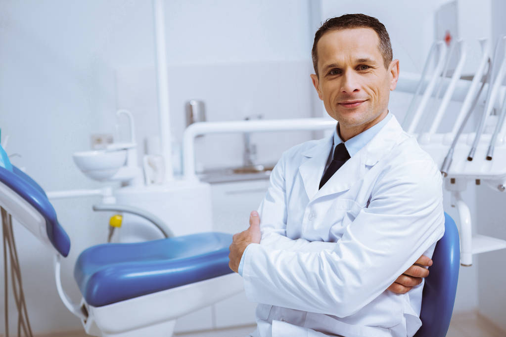 Dentista confiante sentado em seu gabinete
 - Foto, Imagem