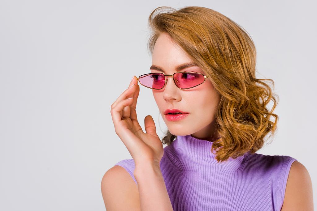 portrait de belle jeune femme aux lunettes de soleil roses regardant loin isolé sur gris
  - Photo, image