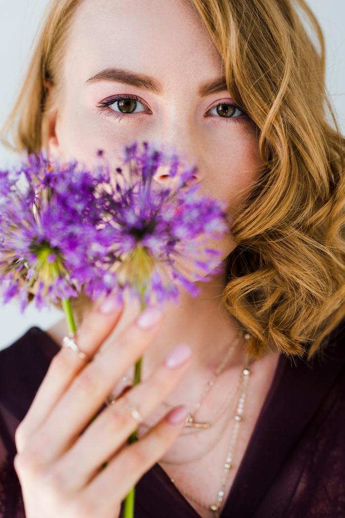 kaunis nuori nainen tilalla tuoreita violetti kukkia ja katsot kameran eristetty harmaa
 - Valokuva, kuva
