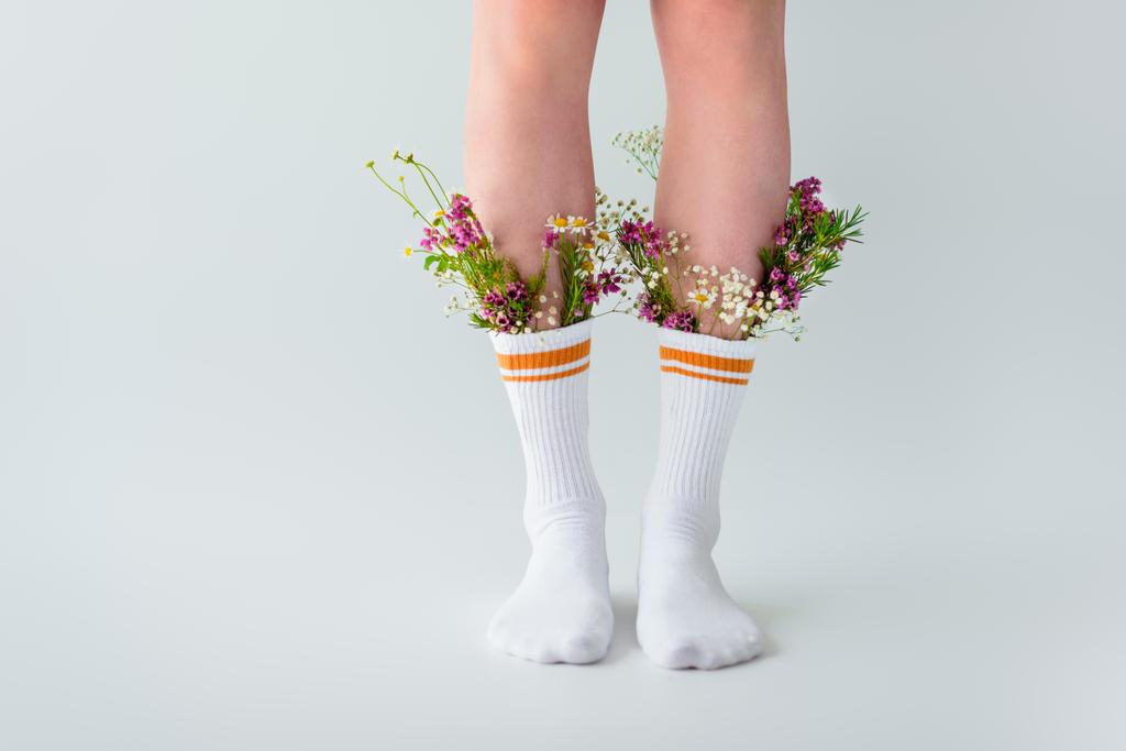 colpo ritagliato di ragazza in calzini con fiori freschi isolati su grigio
   - Foto, immagini