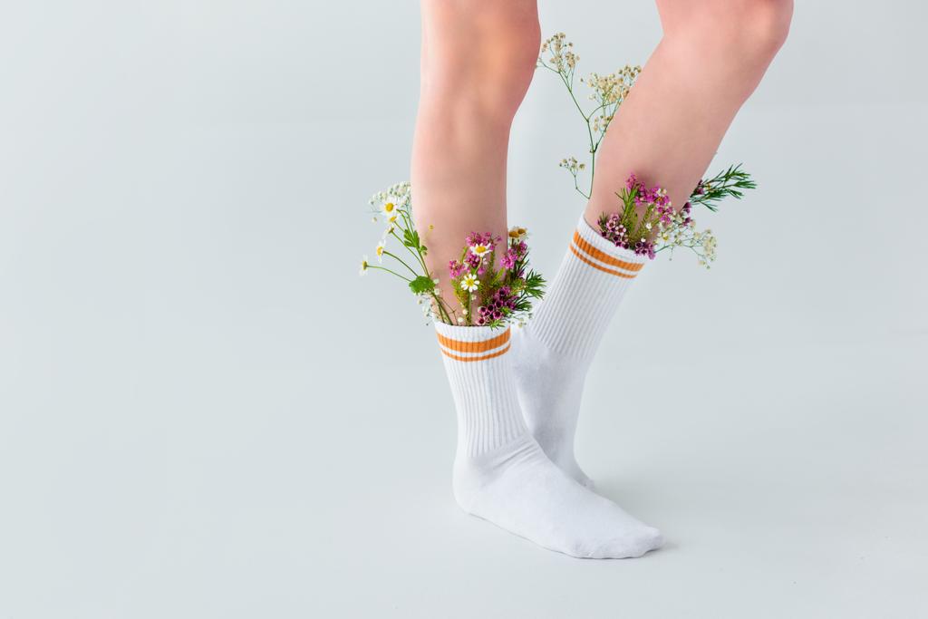 Μερική άποψη του νεαρή γυναίκα σε κάλτσες με όμορφα φρέσκα λουλούδια που απομονώνονται σε γκρι   - Φωτογραφία, εικόνα