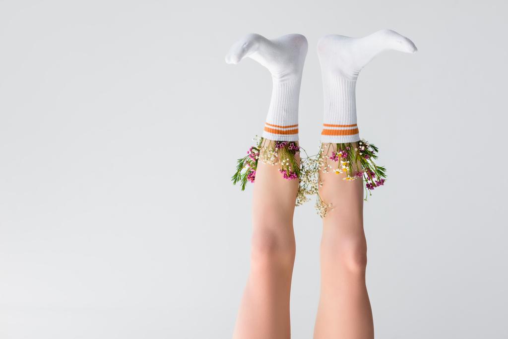 ondersteboven weergave van vrouwelijke benen met bloemen in sokken geïsoleerd op grijs  - Foto, afbeelding