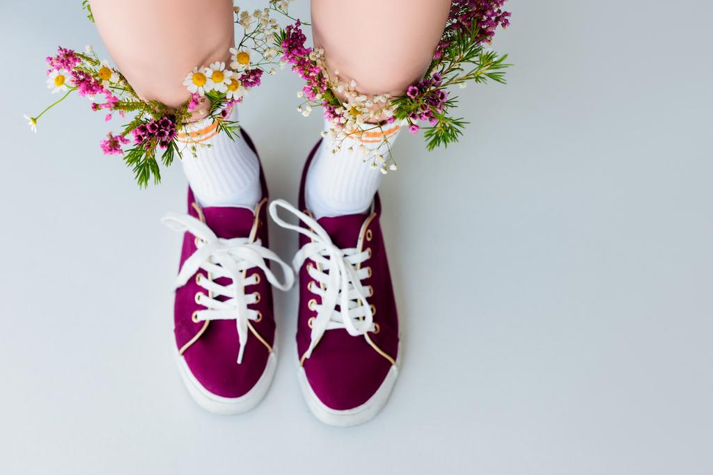 částečný pohled shora z ženských nohou s květinami v ponožky izolované na šedá - Fotografie, Obrázek
