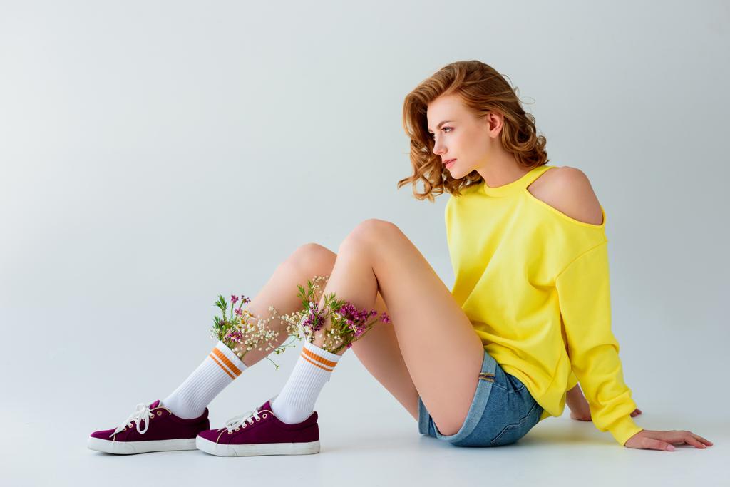 座っていると離れての孤立したグレーを探している靴下で花を持つ美しい少女の側面図 - 写真・画像