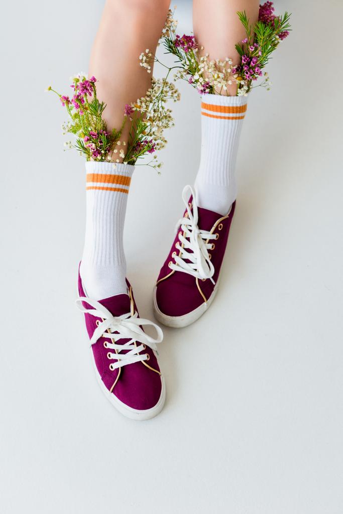 Schnappschuss eines Mädchens mit schönen Blumen in Socken isoliert auf grau - Foto, Bild