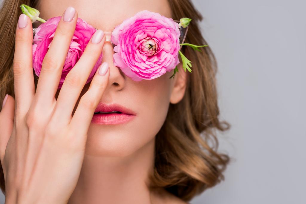 Close-up beeld van meisje aanpassen van brillen met bloemen geïsoleerd op grijs - Foto, afbeelding