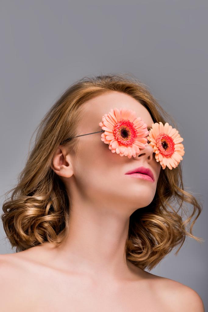 low angle view of naked girl wearing glasses with flowers isolated on grey - Photo, Image