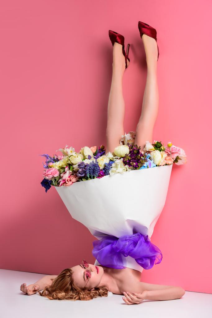 ピンクのドレスで新鮮な花を持つ美しい若い女性の表示が逆さま  - 写真・画像