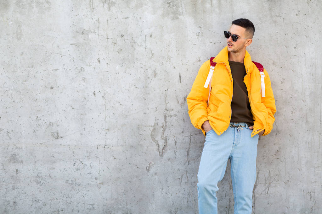 μόδας guy μόνιμη κοντά σε ένα τοίχο με κίτρινα ρούχα - Φωτογραφία, εικόνα