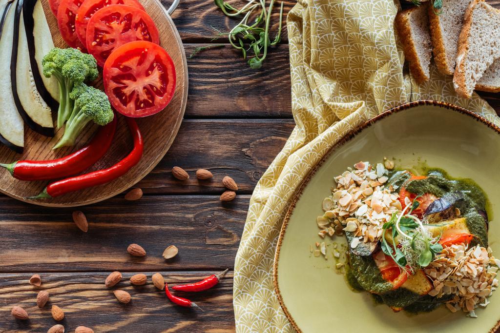 flat lay com salada vegetariana, amêndoas, pimentas, legumes frescos e pedaços de pão em mesa de madeira
 - Foto, Imagem