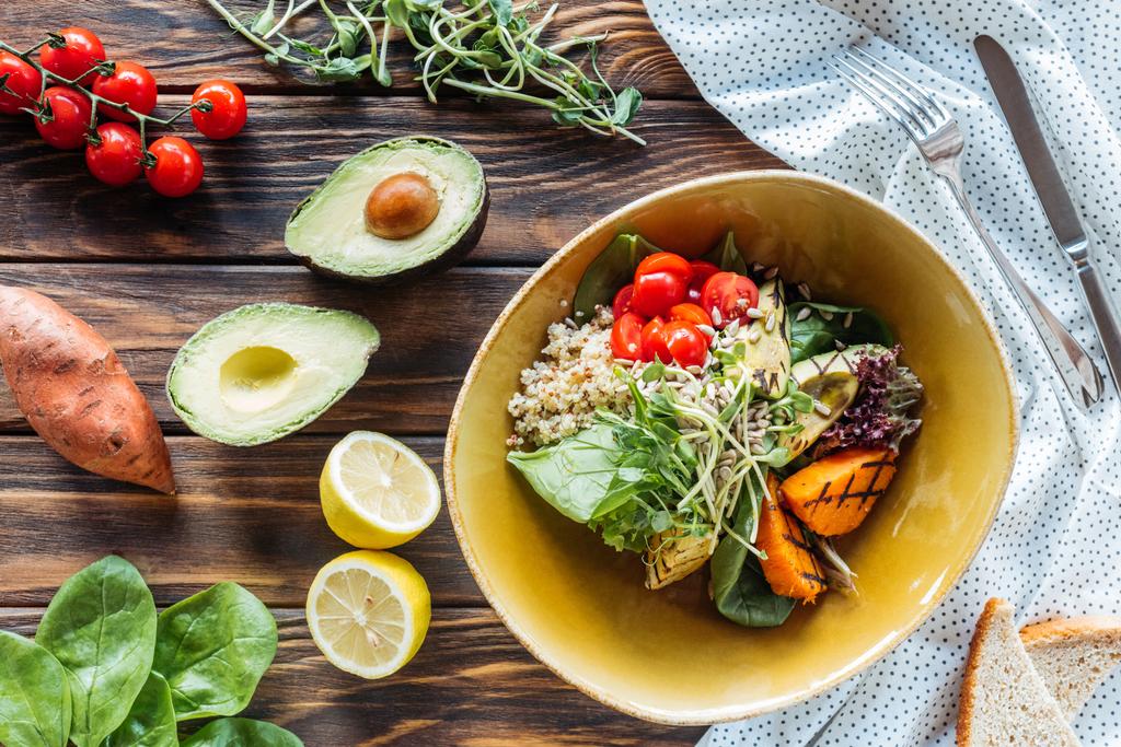 flache Lage mit vegetarischem Salat mit gegrilltem Gemüse und Rosenkohl, Bettwäsche und Besteck auf Holzoberfläche - Foto, Bild