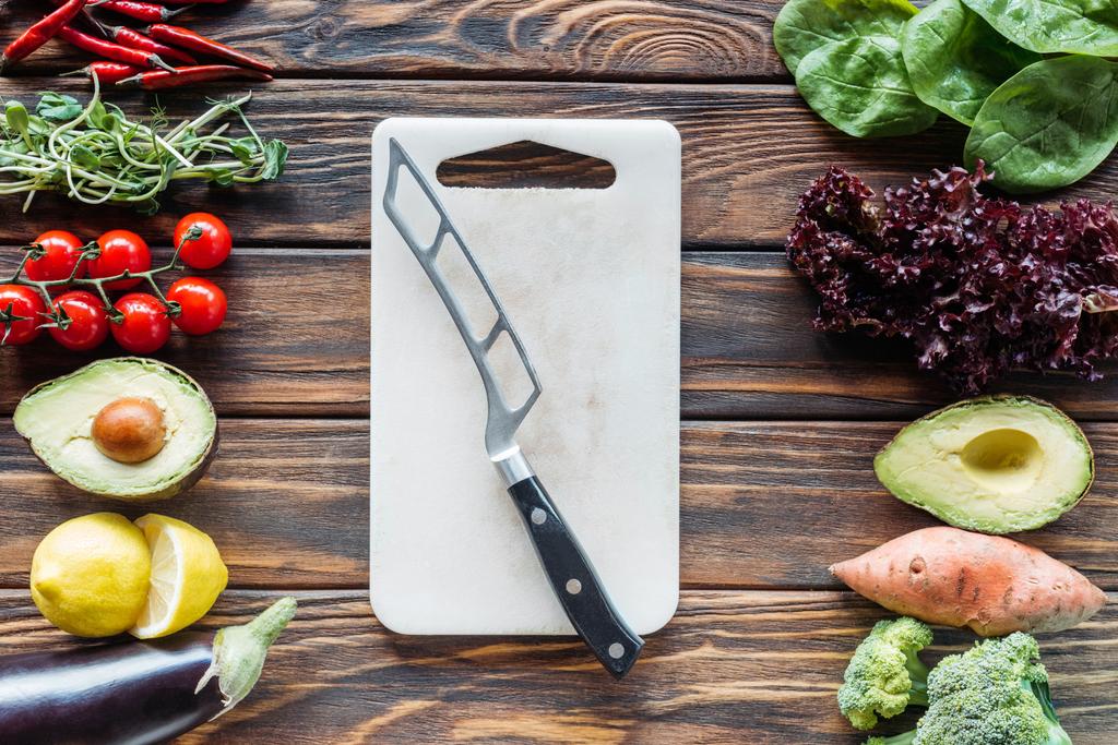Układ płaski z deska do krojenia z nożem i świeżych warzyw, rozmieszczone wokół na drewnianym blatem - Zdjęcie, obraz