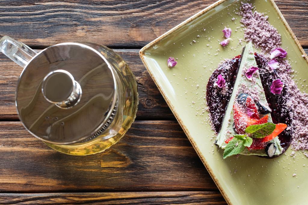 Widok z góry ułożone wegetariański deser z jagodami na talerz i czajniczek na powierzchni drewnianych - Zdjęcie, obraz