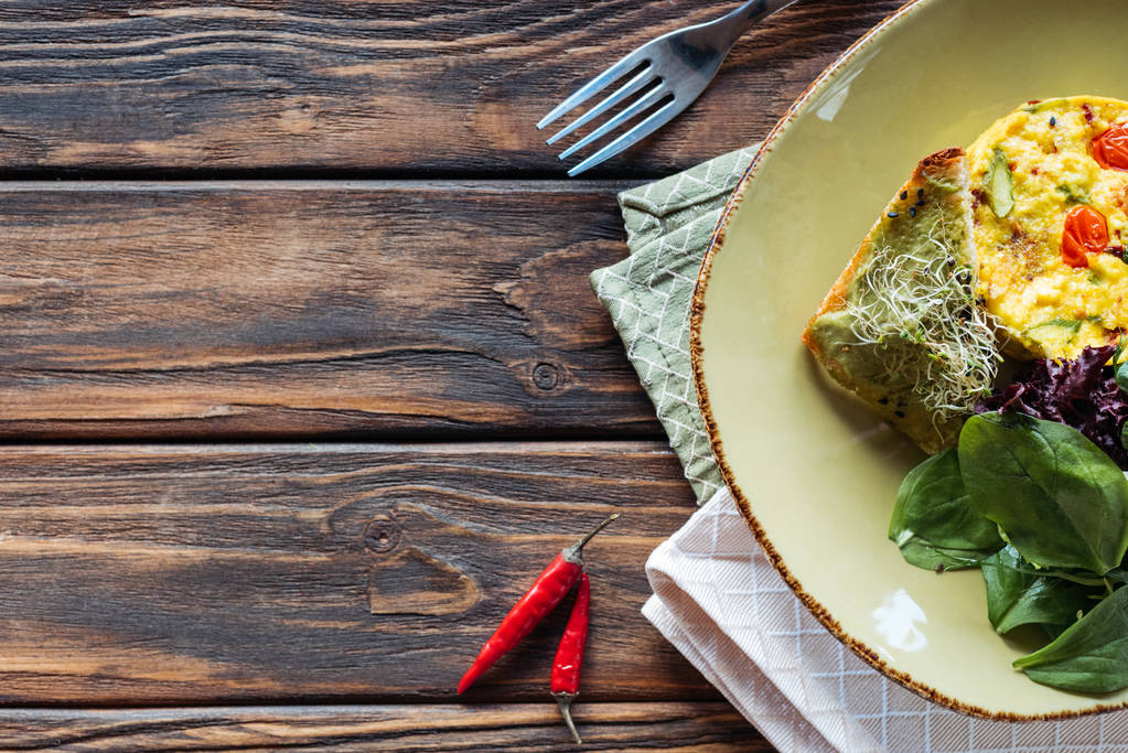 vista dall'alto dell'insalata vegetariana con spinaci e germogli su piatto, peperoncino e forchetta su tavolo di legno
 - Foto, immagini