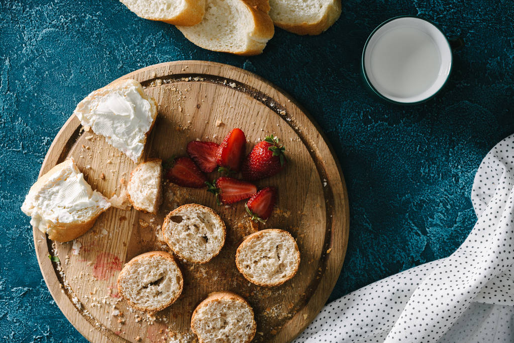 Tagliere con fragole e panini con crema di formaggio sul tavolo blu
 - Foto, immagini