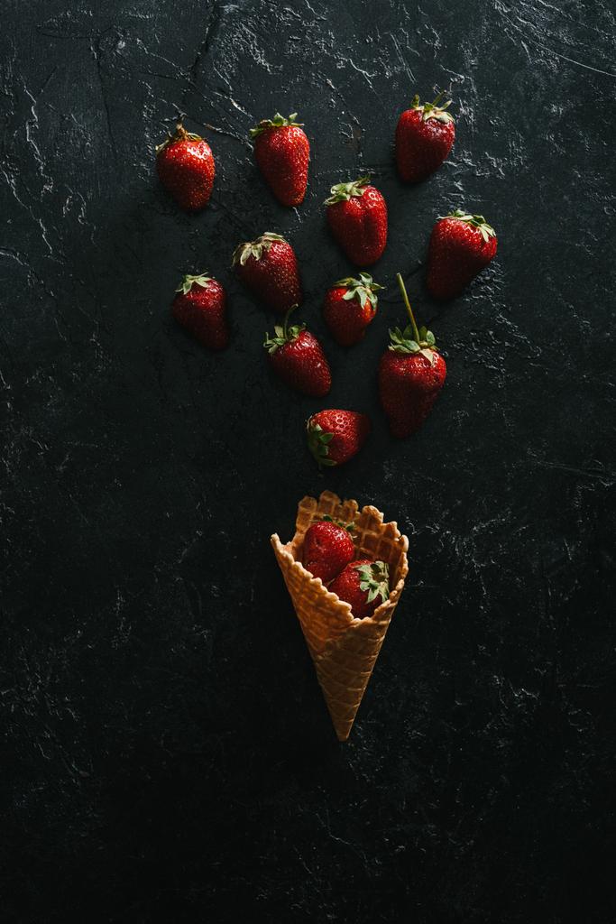 top view of red strawberries by waffle cone on dark background - Photo, Image