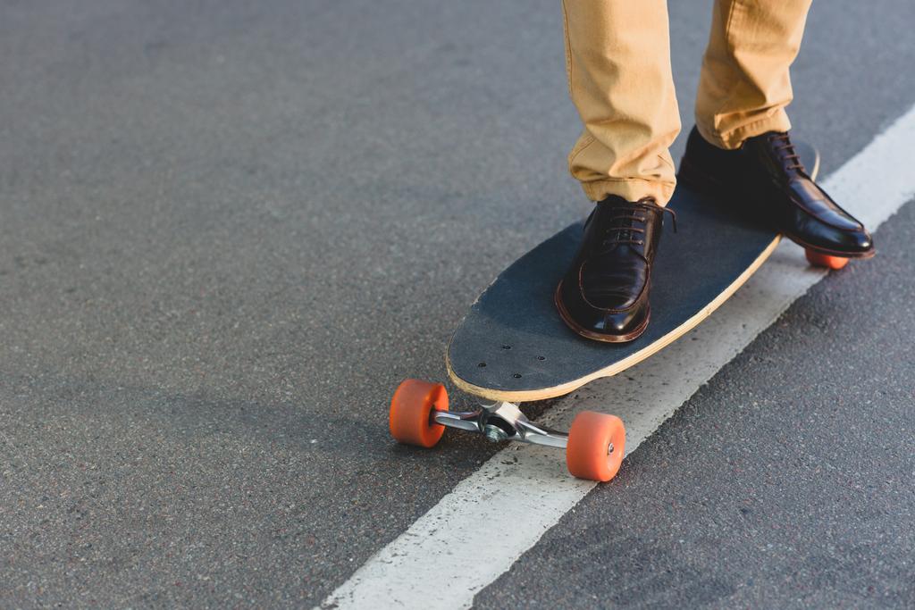 bijgesneden schot van jonge man die op skateboard op de straat   - Foto, afbeelding