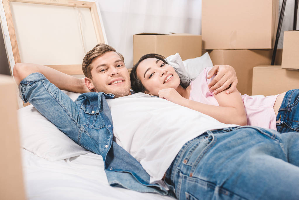 beautiful young couple relaxing on bed while moving into new home - Photo, Image
