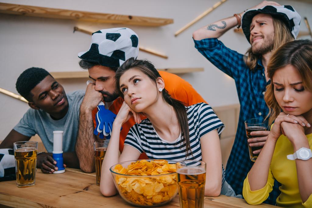sconvolto gruppo di amici multietnici in cappelli da pallone da calcio guardando partita di calcio al bar
  - Foto, immagini
