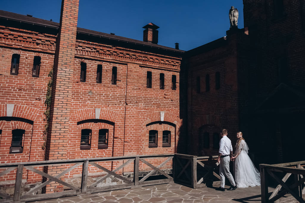 Braut und Bräutigam spazieren vor altem Gebäude - Foto, Bild