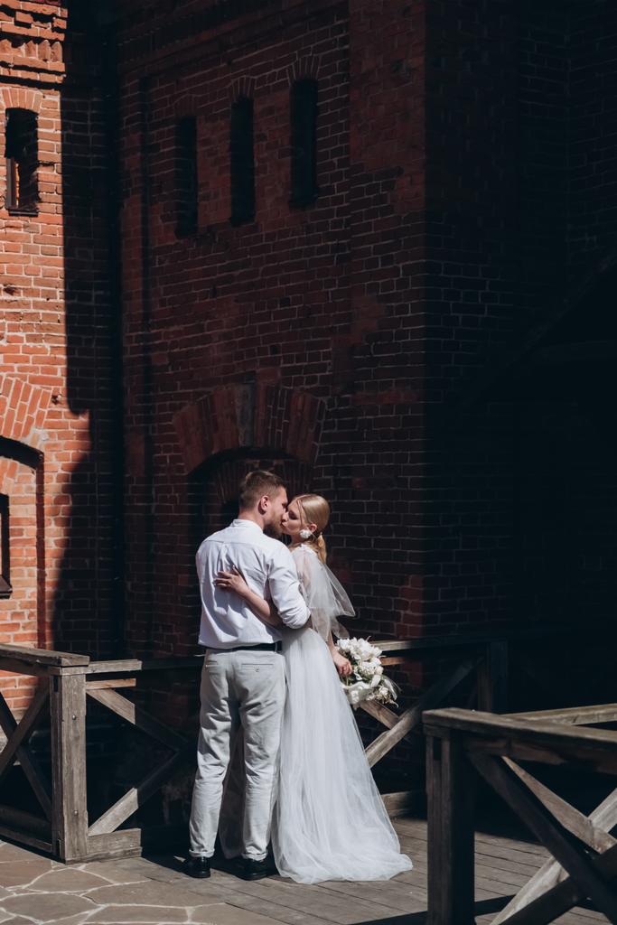 Braut und Bräutigam küssen sich vor altem Festungsgebäude - Foto, Bild